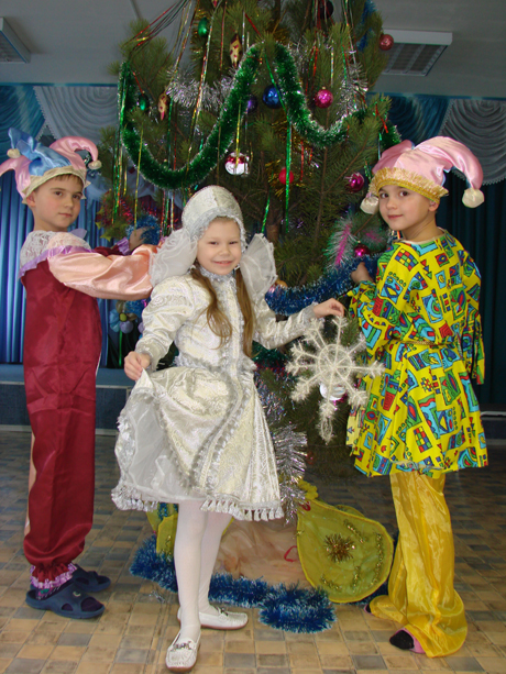 Петрушки Саша Минченко и Кирилл Баранов вместе со Снегурочкой Алиной Варфоломеевой наряжают елку.