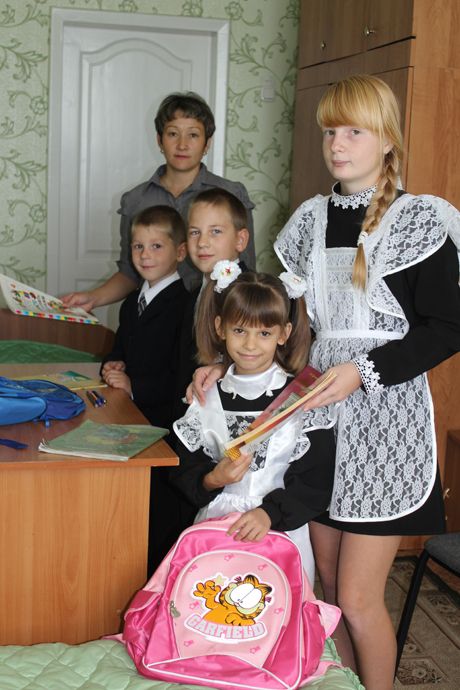 Люда Куликова и Данила Минаев вместе с воспитателем А.О. Шариповой помогают Илье и Тае собрать портфели.